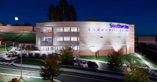 Artist's rendering of the new building, shown at night, three story structure with several parking spots out front.