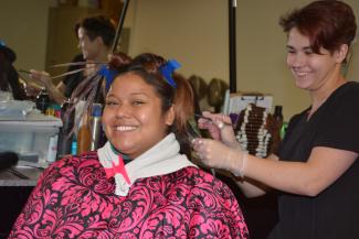 A female student trims on a female client's hair inside SCC's Cosmetology lab