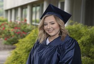 Young woman smiling in a graduation cap and gown