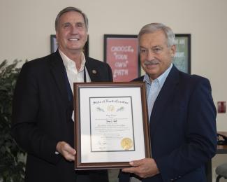 Two men hold up a plaque
