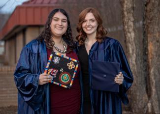Two graduates smile outside Balsam Center on the SCC Jackson Campus