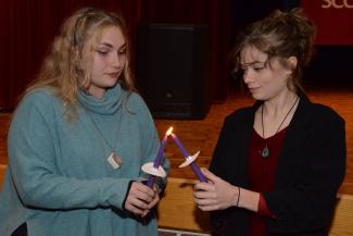 Student lights a fellow inductees candle during the ceremony.