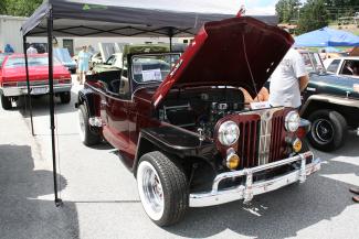 Photo of red convertible vehicle with hood up and top down.