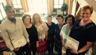 A group of six ladies and one man stand on a stairway inside a building on SCC's Macon Campus