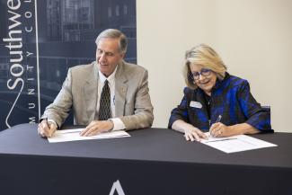 Two people signing documents