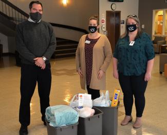 Two SCC employees present tubs filled with donations to man representing HERE.
