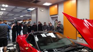 Students surround a red sports car at Passion Performance