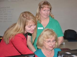 Photo of three ladies looking at a computer screen.