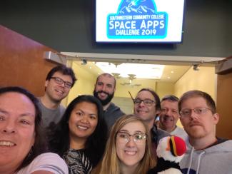 Group of mentors and young competitors stand outside a conference hall for NASA scientific competition held at SCC.