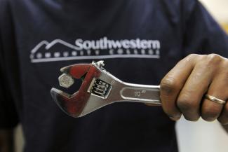 A man holds a magnetic wrench that has a bolt clinging to the top.