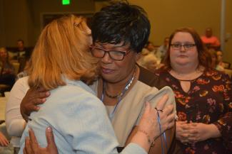 Woman hugs her instructor after receiving her pin.