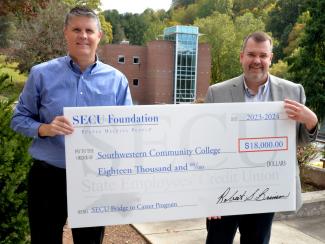 Two men hold a large check