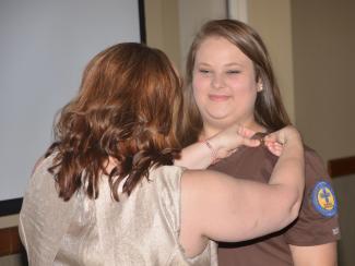SCC Nurse Aide graduate receives pin from her program coordinator.