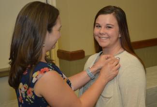 A student smiles at the camera as her instructor pins her