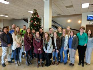 Group of people stand in front of Christmas tree