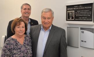 Three people stand beside a plaque
