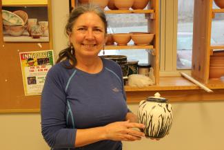 Woman holds a piece of pottery she made