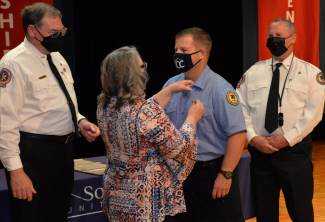 Loved one applies pin to graduate as instructors look on.