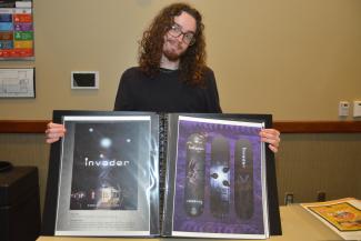 Male student holds his portfolio open to show two designs he created while attending classes at SCC.