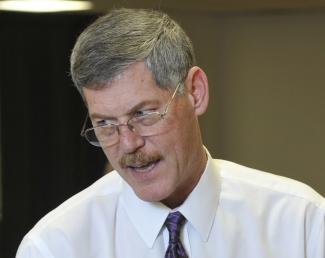 An instructor points out correct techniques for dealing a card game at a casino-like table.