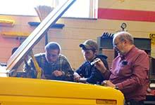 Photo of Bobby Price (right) and students Ryan Younce (left) and Jesse Peavy examine an engine in Franklin High School’s automotive lab.