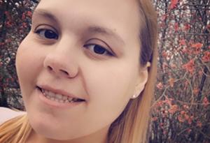 A young woman smiles for a selfie while surrounded by flowers