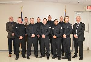 A group of law enforcement graduates huddle together for a group picture with their instructors.