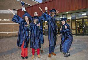 A group of graduates strike fun poses in their caps and gowns.