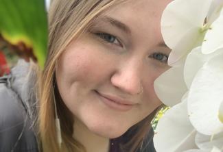 Young blonde female smiling among some flowers
