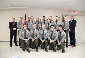 A group of recent law enforcement graduates huddle inside for a group picture.